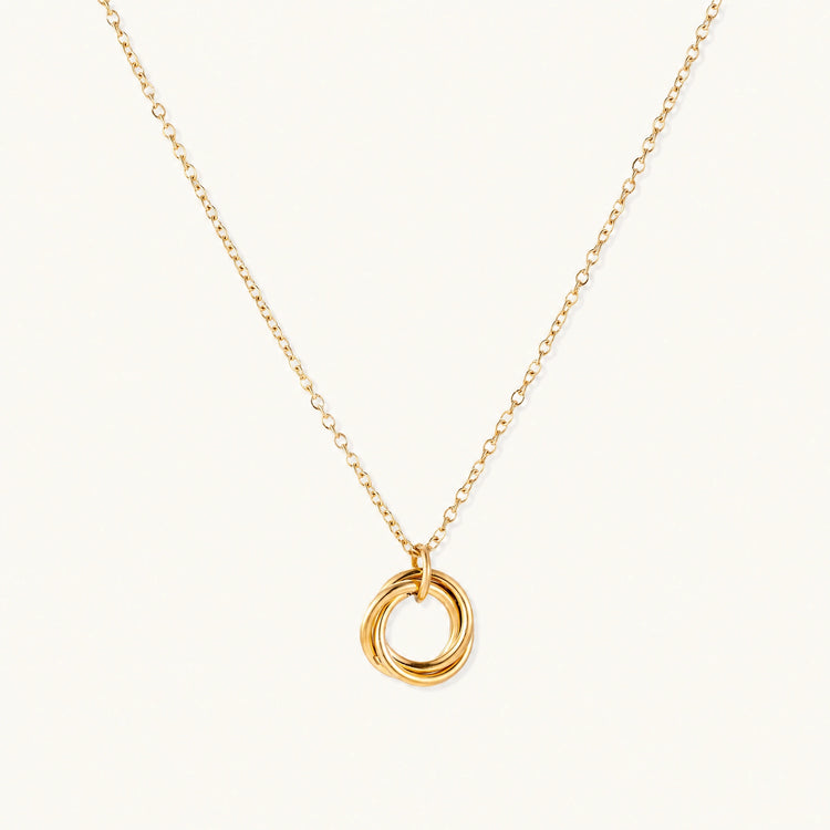 Delicate gold-plated necklace with three interlocking circle rings forming a minimalist knot pendant on cream background